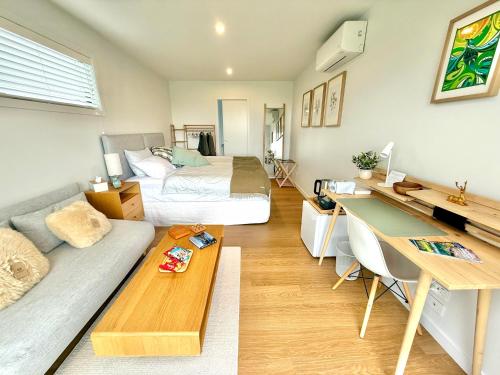 a room with a bed and a desk and a couch at The Mann Homestay, Premium King Room with Private Ensuite, Near Waihi & Coromandel in Waihi