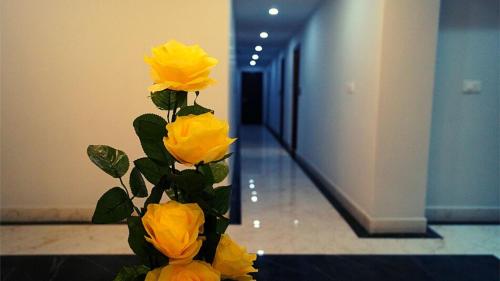 a vase filled with yellow roses in a hallway at Staynest Continetal With parking Near Mg Marg in Gangtok