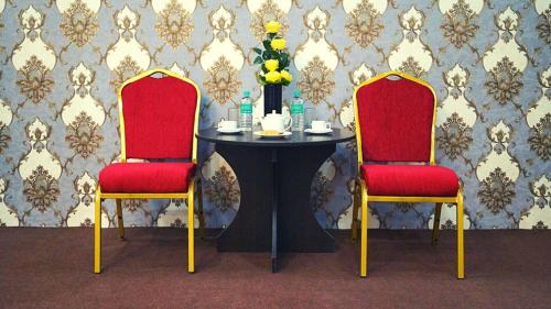 two red chairs and a table with a vase of flowers at Staynest Continetal With parking Near Mg Marg in Gangtok