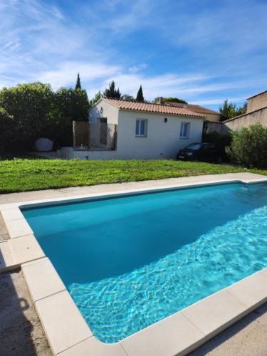 a blue swimming pool in front of a house at Tiny House T1 in Entraigues-sur-la-Sorgue
