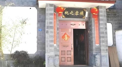a building with a pink door with chinese writing on it at Lijiang Peach Hostel in Lijiang