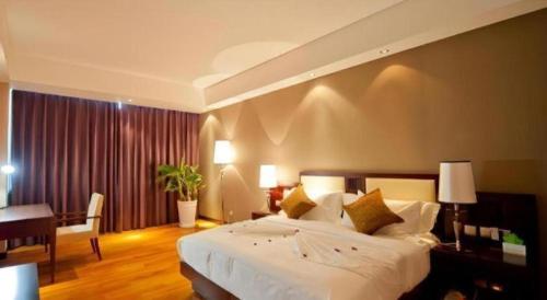a bedroom with a large white bed and a desk at Kunming Wenhui Hotel in Kunming
