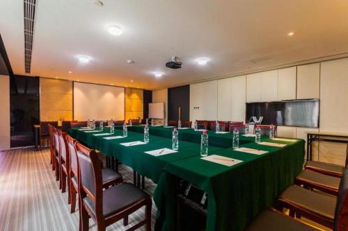 a conference room with a long green table and chairs at Jinjiang Metropolo Hotel - Qingdao Chengyang District Government in Qingdao