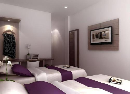 a room with two beds and a tv on the wall at Amantis Hotel in Demak