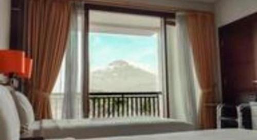 a bedroom window with a view of a mountain at The Oxalis Regency Hotel in Magelang