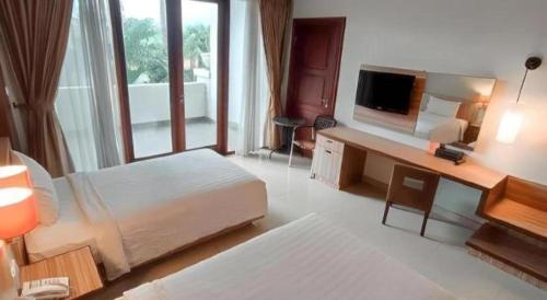 a hotel room with a bed and a desk with a television at The Oxalis Regency Hotel in Magelang