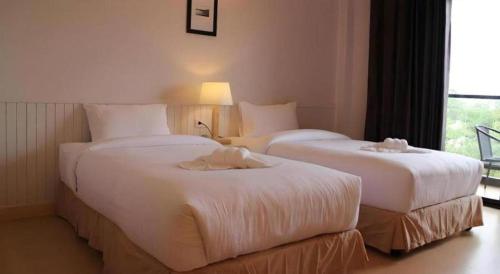 two beds in a hotel room with white sheets at Villa Gris Pranburi in Pran Buri