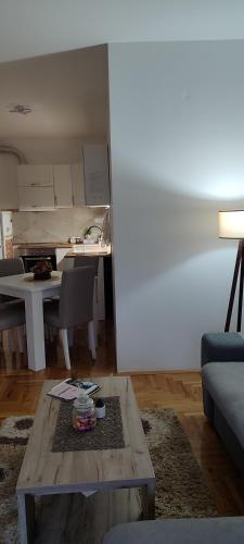 a living room with a table and a kitchen at Apartman N&L in Sombor