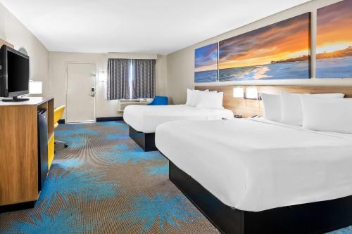 a hotel room with two beds and a flat screen tv at Days Inn by Wyndham Goose Creek in Charleston