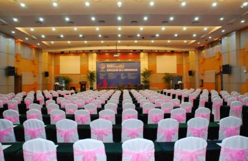 a large room with white chairs and a screen at Huangshan International Hotel in Huangshan