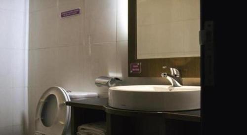 a bathroom with a sink and a toilet with a mirror at Hotel D' CaLia Tarakan in Tarakan