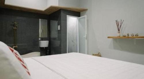 a bedroom with a white bed and a bathroom at Kenari Tower Hotel in Makassar