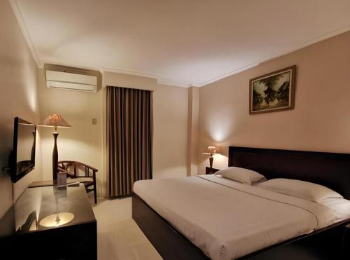 a hotel room with a large bed and a table at Plaza Hotel Tegal in Tegal