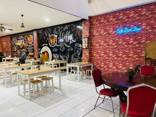 a restaurant with tables and chairs and a brick wall at Hotel Huswah Airport in Jakarta