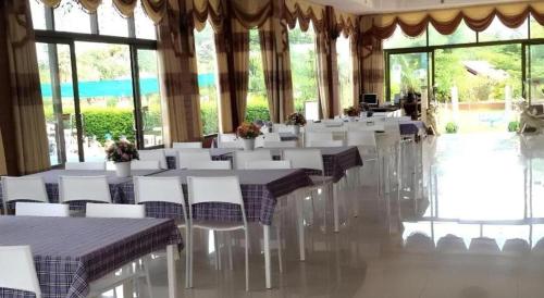 a banquet hall with white tables and chairs and windows at Lomdao Resort in Udon Thani