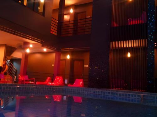 a hotel with red chairs and a swimming pool at Nangfa Mini Hotel in Chiang Rai