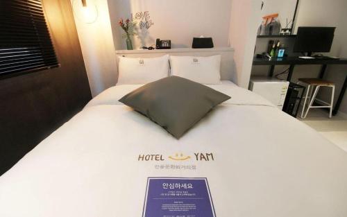 a bed in a hotel room with a sign on it at Hotel Yam ANDONG in Andong