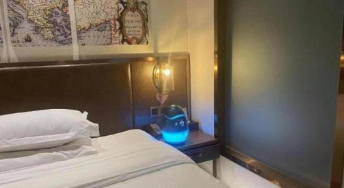 a bedroom with a bed and a nightstand with a blue lamp at James Joyce Coffetel Xi'an Lingtong The Terracotta Army Huaqingchi University Town Metro Station in Xi'an