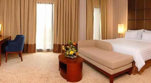a bedroom with a bed and a chair and a desk at Labersa Grand Hotel &Convention Center in Pekanbaru