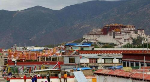a group of buildings with mountains in the background at Tashitakge Hotel in Lhasa
