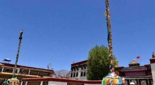 a building with two poles in front at Tashitakge Hotel in Lhasa