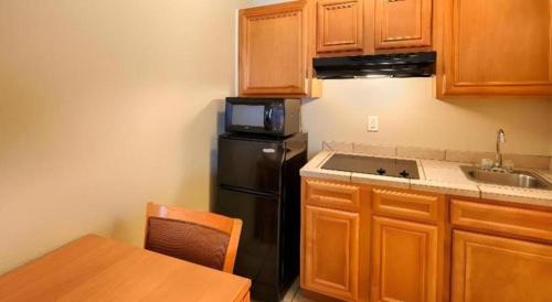 a kitchen with a black refrigerator and wooden cabinets at Best Western Plus Guymon Hotel and Suites in Guymon