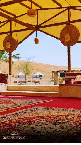 a room with a yellow umbrella and a red carpet at Al Salam Desert Camp Bidiya in Bidiyah