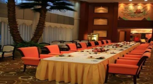 a long table in a room with red chairs at Dunhuang Grand Soluxe Hotel in Dunhuang