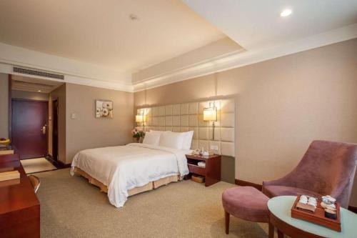 a hotel room with a bed and a desk and chair at Best Western Plus Fuzhou Fortune Hotel in Fuzhou