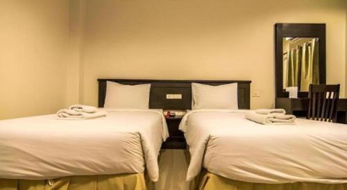 two beds in a hotel room with towels on them at At Home at Udon in Udon Thani