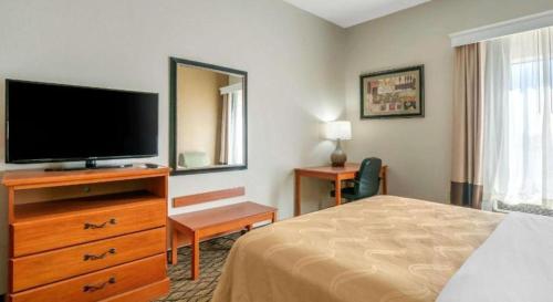 a hotel room with a bed and a flat screen tv at Quality Inn & Suites Jefferson City in Jefferson City