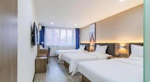 a hotel room with three beds and a desk at 7 Days Inn Tianjin Development Zone 3rd Street Wanli in Binhai