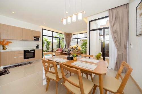 a kitchen and dining room with a wooden table and chairs at Goldena Residence Private Pool Villas in Kamala Beach