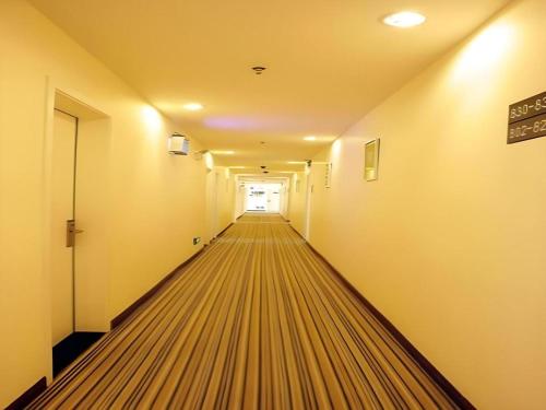 an empty corridor with a long hallway with a door at 7 Days Inn Hohhot Hailiang Xinhua Square Metro Station in Hohhot