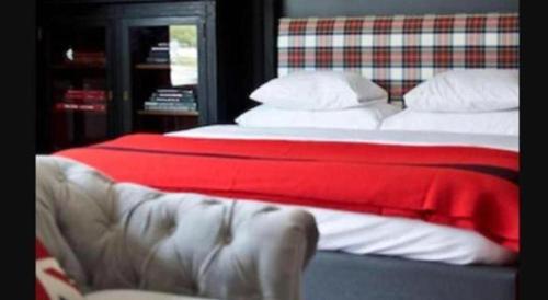 a bed with a red blanket and a couch at The George Montclair in Montclair