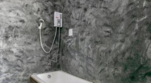 a stone bathroom with a bath tub and a shower at OYO 75374 Baan Rak Mai in Kanchanaburi