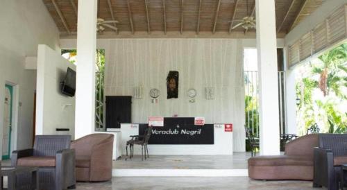 a lobby with couches and a counter with a wantedverbverb sign at Merrils Deluxe in Negril