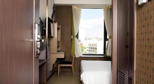 a small bedroom with a bed and a window at Largos Hotel in Hong Kong