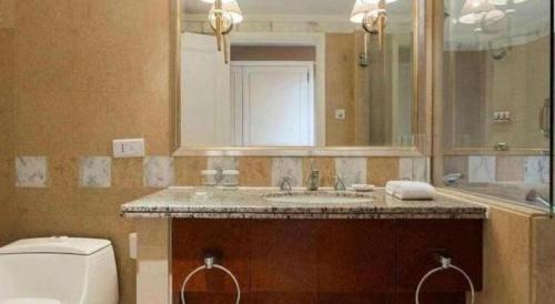 a bathroom with a sink and a toilet and a mirror at Kai Wah Plaza International Hotel in Kunming