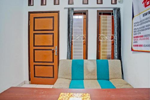 a living room with a couch in front of a door at Hotel O Penginapan Hj Lilis 2 Syariah in Sukabumi