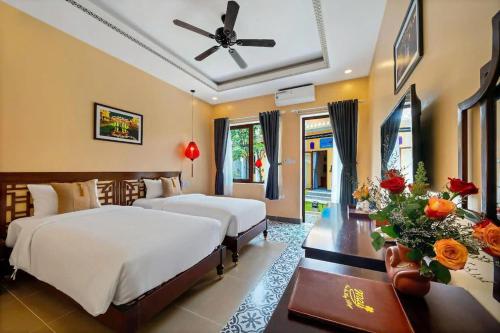 a bedroom with two beds and a ceiling fan at Zen B Hoian Villa in Cam Thanh