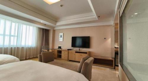a hotel room with a bed and a flat screen tv at Ramada Plaza Shenyang Citycenter in Shenyang