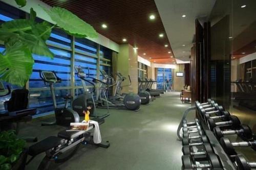 a gym with several treadmills and exercise bikes at New Century Grand Hotel Zhuji Yaojiang in Shaoxing