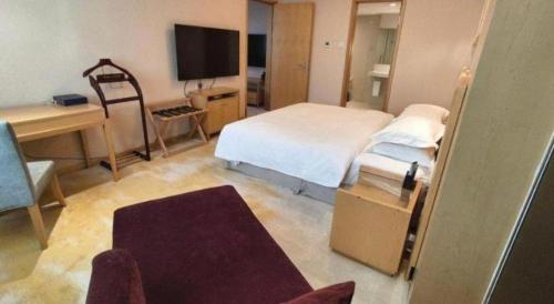a bedroom with a bed and a desk and a television at Ramada Plaza Shenyang Citycenter in Shenyang