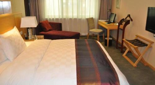 a hotel room with a large bed and a desk at Ramada Plaza Shenyang Citycenter in Shenyang