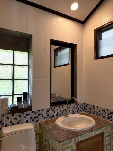 a bathroom with a sink and a toilet and a mirror at Kai Bae Beach Resort Koh Chang in Ko Chang