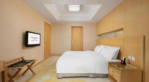 a bedroom with a white bed and a tv at Ramada Plaza Shenyang Citycenter in Shenyang
