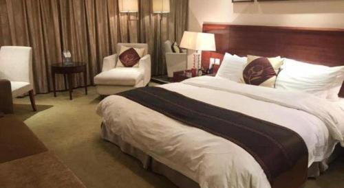 a hotel room with a large bed and a chair at Ramada Plaza Shenyang Citycenter in Shenyang