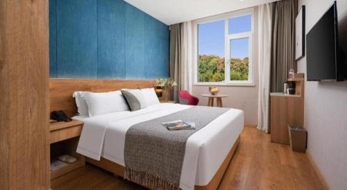a hotel room with a large bed and a window at New Beacon Sunyee SPA Hotel in Wuhan