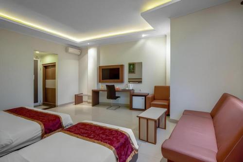 a hotel room with two beds and a desk at Raffleshom Hotel in Bandung